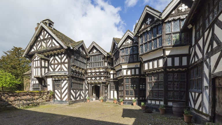 North view of the courtyard and north face of Little Moreton Hall's black-and-white Tudor house.